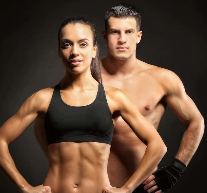 Fit couple with toned physiques posing in a studio